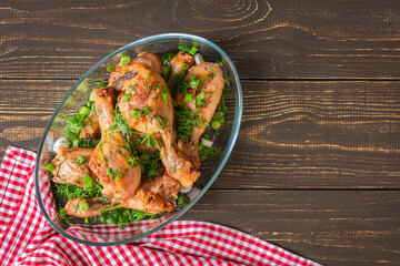 Baked chicken drumsticks with rosemary, spices, onions and dill on a wooden background , top view
