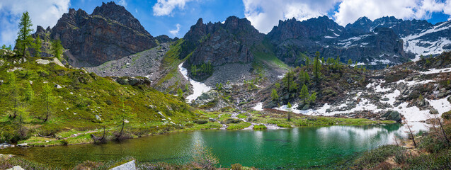 Alpine lake in idyllic environment amid rocks and forest. Natural reservoir of fresh water at high altitude on the mountains.