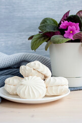 Marshmallows. Vanilla sweet homemade marshmallows. Light composition with a flower in a pot. Violet flower. Sweet delicious dessert.