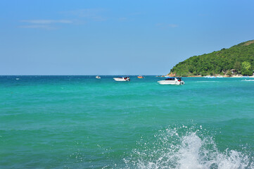 tropical beach with crystal clear turquoise water clear blue sky with boats in the water