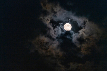 Naklejka na ściany i meble Full Moon peaking through beautiful cloudscape