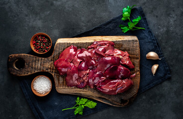 
Raw chicken liver on a cutting board on a stone background. View from above. Space for text