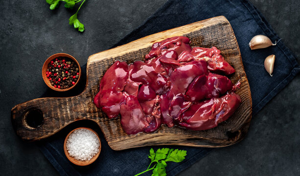 
Raw chicken liver on a cutting board on a stone background. View from above. Space for text