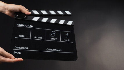 Fototapeta na wymiar A Hand is holding Black clapper board or movie slate use in video production, movie, film, cinema industry on black background. It has written in number.