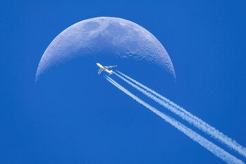 Passenger plane - airliner passes near the moon. Explore new frontier. Space traveler concept - obrazy, fototapety, plakaty