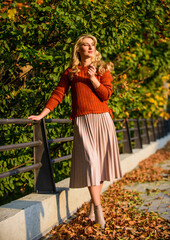 Obraz na płótnie Canvas Autumn woman. girl walk in park. girl in corrugated skirt and sweater. Pleated trend. sunny day with fallen leaves. fall fashion season. female beauty. Femininity and tenderness. autumn woman outdoor