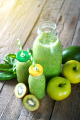 Glass bottles with green smoothies made with green fruits. Detox and healthy diet background.