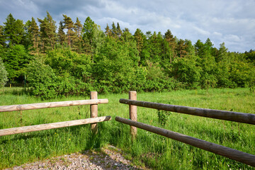 Fototapeta na wymiar Summer rural landscape on a sunny day. Fence against the background of meadows and forest, Kashubian, Poland