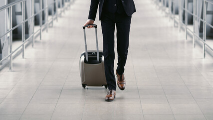 Urban business man walking in airport with suitcase