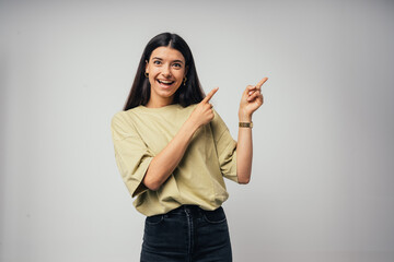 Young handsome caucasian girl  indicates something with his hands. Isolated on gray background
