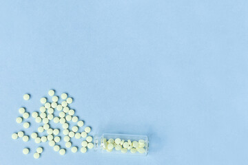 Tablets and a glass bottle on a blue background. Medicine, healthcare and tablets concept. Flatley. The view from the top. copyspace for text. yellow tablets on a pastel blue background