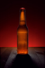 beer in a bottle on a wooden table with a backlit background. Cold drink in a bottle.