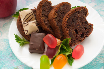 Chocolate cake and jelly candies on a white plate with mint