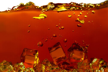 Closeup process of making cool black tea. Macro shot of dipping, falling ice cubes into transparent...