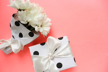 gift concept. bouquet of white flowers and gift box on a pink background