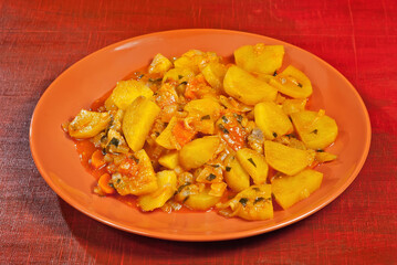 Potatoes in a garlic plate on a wooden table. Boiled potatoes with orange sauce.