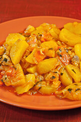 Potatoes in a garlic plate on a wooden table. Boiled potatoes with orange sauce.