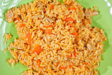 Pilaf with meat and carrots in a green plate.