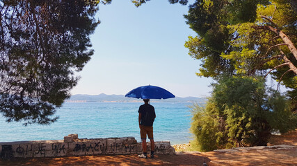 A man holding an umbrella in front of the Adriatic Sea, Zadar, Croatia