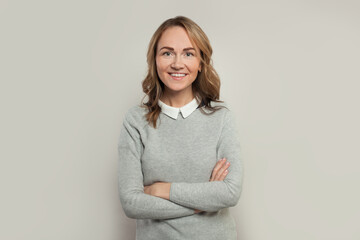 Obraz premium Happy casual woman with crossed arms smiling on white background, portrait