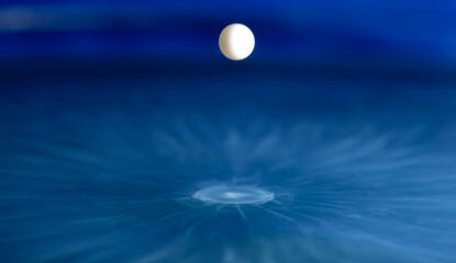 A White Liquid Sphere Suspended on a Blue Surface