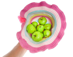 Green apples in a colorful straw hat towards white held in one hand