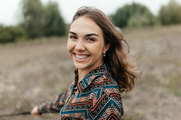 Young smiling woman in shirt walking in nature