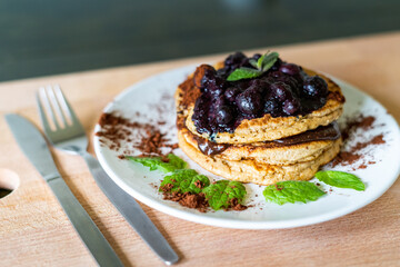 Delicious oats American pancakes with homemade chocolate toping, cooked blueberries and fresh mint leafs. Healthy lifestyle cooking