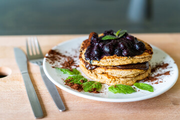 Delicious oats American pancakes with homemade chocolate toping, cooked blueberries and fresh mint leafs. Healthy lifestyle cooking