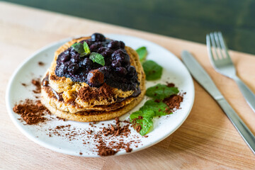 Delicious oats American pancakes with homemade chocolate toping, cooked blueberries and fresh mint leafs. Healthy lifestyle cooking