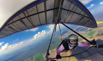Happy smiling girl hang glider pilot shows thumb up high in the sky. - obrazy, fototapety, plakaty