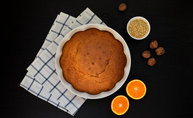 orange and walnut cake on black background.