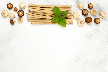 Raw pasta made of mushrooms with fresh basil leaves and fresh mushrooms on light concrete background.Top view,copy space.