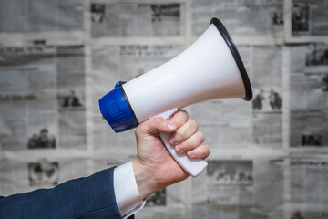 A man holding a megaphone on background of newspapers. News message concept. Concept for news and...