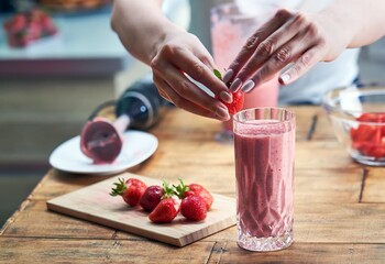 Woman making strawberry smoothie. Healthy refreshment and summertime concepts.