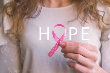 Girl holds pink cancer ribbon, breast cancer, awareness month, hope phrase
