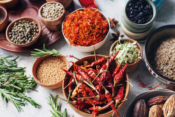 Colorful indian spices and herbs in bowls on light concrete table