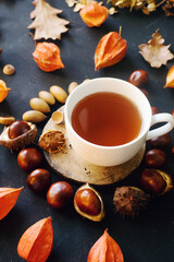 Cozy composition with hot tea, dried autumn leaves and nuts