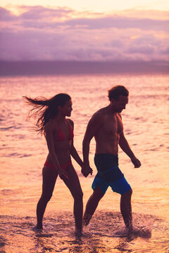 Beach couple walking on romantic sunset summer travel vacation silhouettes Sunset Caribbean tropical destination holidays woman and man young lovers relaxing on romance getaway.