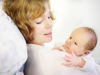 Mother holding her tiny newborn baby. Woman enjoy her first day's as a young mom with cute infant child. Mother day.
