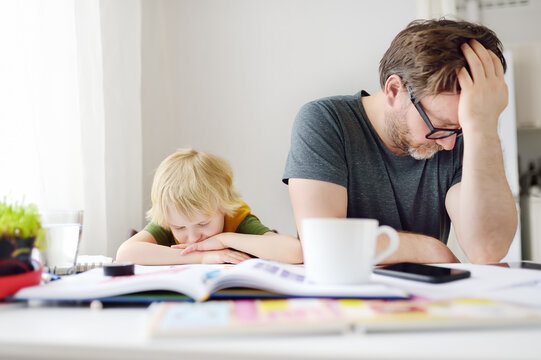 Tired And Angry Father Trying Help Son Doing His Homework, But Bored Child Refusing. Homeschooling, Online Studying, Remote Education For Kids During Quarantine Is A Problems For Parents.