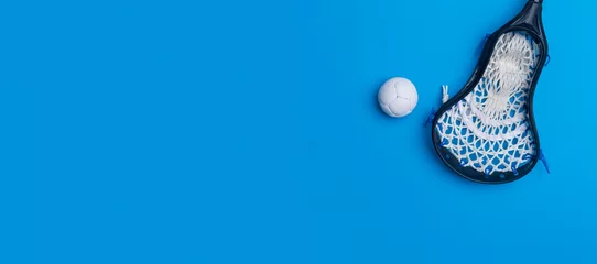 Foto op Plexiglas Lacrosse stick and white  ball on blue background. Lacross is a team sport © Augustas Cetkauskas