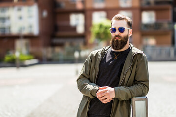 Obraz premium Young brutal bearded man near handsrails outdoors on sunny street
