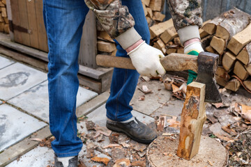 A man chopping birch firewood (logs) with a metal ax with a wooden handle. Logging firewood for the fireplace.