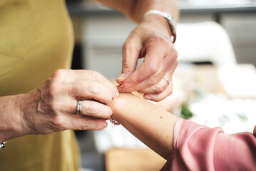 Elderly woman helping young woman to dress. Close up of hands fastening bracelet on wrist.