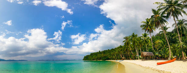 The panorama of a tropical beach with white sand. A small resort with a modest beach infrastructure. Kayak lays on the send.