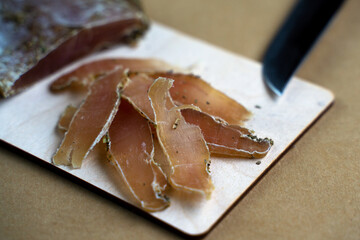 The pieces of thinly sliced dried meat lie on the cutting board