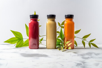 Red, orange and yellow smoothies and juices beverages in bottles with various fresh organic fruits and berries ingredients
