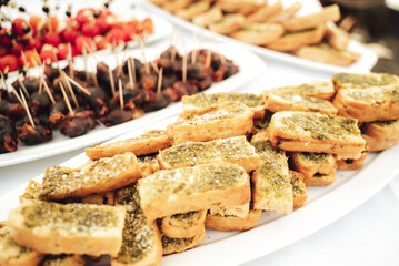 Self-service buffet table with various types of small snacks. Focused on baguette smeared with basil pesto. Celebration, birthday, party, wedding