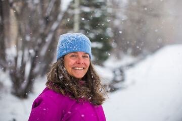 A portrait of a happy middle aged woman enjoying a beautiful snowfall in a cold Colorado, USA
